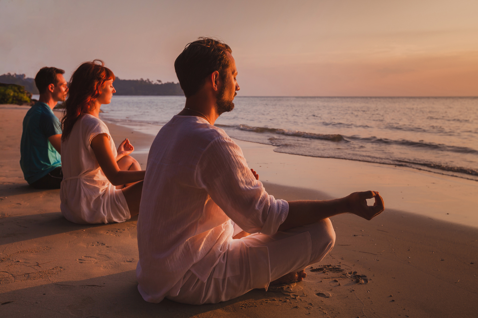 group meditation, people practicing yoga on the beach, relaxation